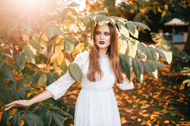 Beautiful girl with gothic make up and funny face expression posing in summer park  - Foto, Imagem