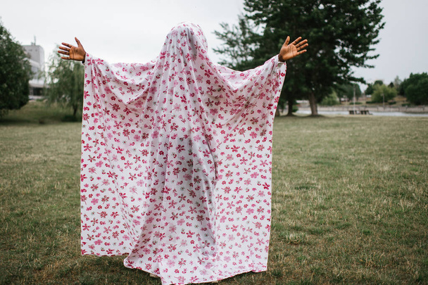 African american man covered in ghost costume posing outdoor in autumn park. - Foto, immagini