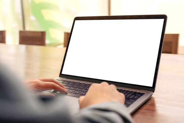 Образец изображения женщины, использующей и печатающей на ноутбуке с белым экраном рабочего стола на деревянном столе в офисе - Фото, изображение
