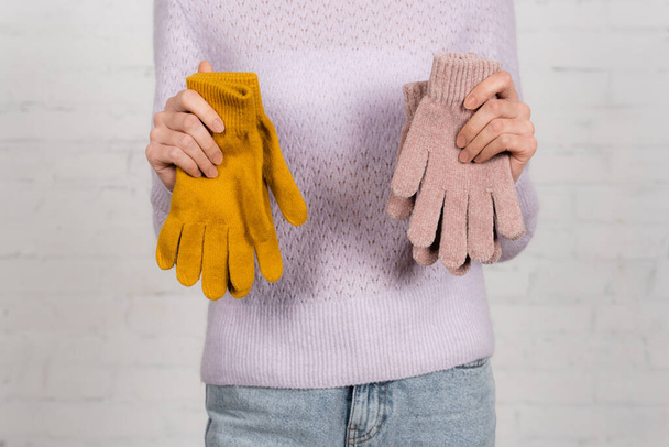 白い背景に暖かい手袋を保持セーターの女性の作物ビュー - 写真・画像