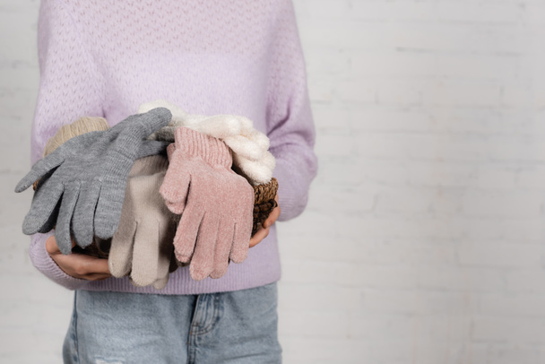 Ausgeschnittene Ansicht der Frau hält Korb mit weichen Handschuhen auf weißem Hintergrund - Foto, Bild