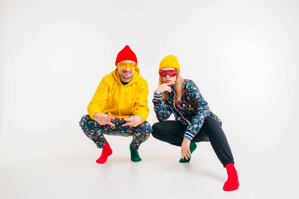 Stylish couple of man and woman in colorful clothes posing over white background - Фото, изображение