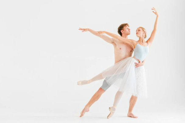 Young couple of modern ballet dancers posing over white studio background - Foto, Imagen