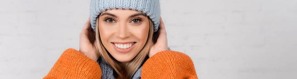 Positive woman in sweater and hat looking at camera on white background, banner  - Photo, image