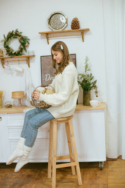 girl in warm light knitted sweaters in the kitchen with cups of warm cocoa - Фото, зображення