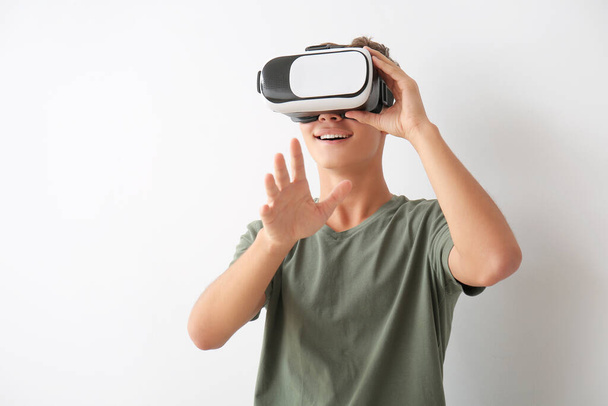 Teenage boy with virtual reality glasses on light background - Φωτογραφία, εικόνα
