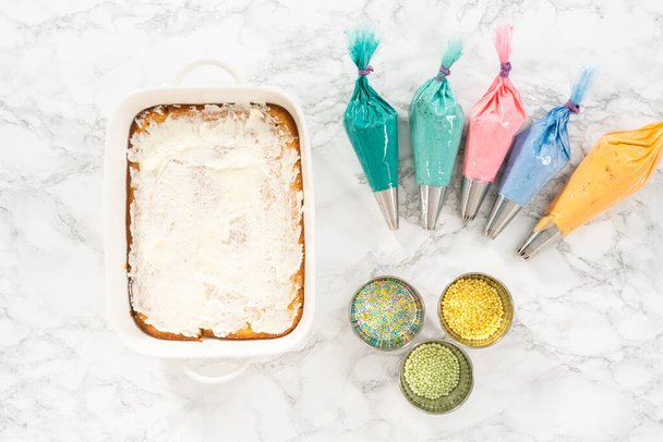 Лист торт готов быть украшен красочной глазурью масляного крема. - Фото, изображение