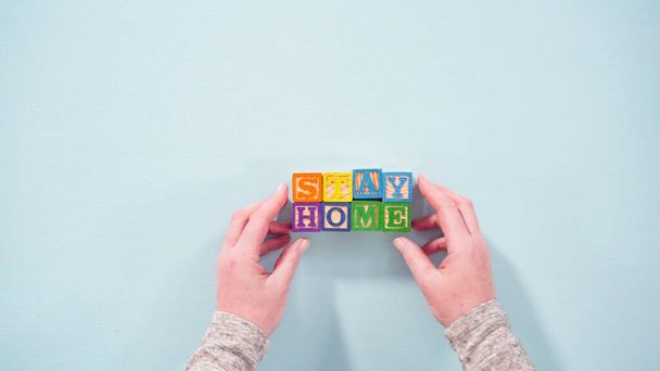 Flat lay. STAY HOME sign out of kids' alphabet blocks with homemade face masks on a white background. - Fotografie, Obrázek