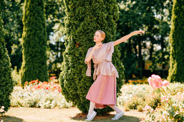 Young graceful female ballet dancer in theatrical dress posing in sunny park - Foto, Bild