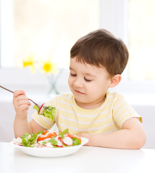 Cute little boy is eating vegetable salad - Foto, imagen