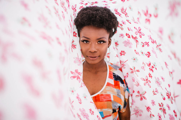 Modeporträt eines afrikanisch-amerikanischen Mädchens im Cover mit Blumen-Print - Foto, Bild