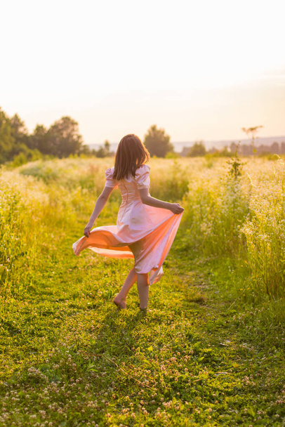 dziewczyna działa przez pole w różowej sukience - Zdjęcie, obraz
