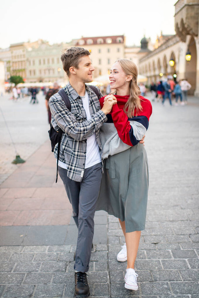 Happy loving couple smiling and walking throug the main square in Krakow (Cracow) - Valokuva, kuva