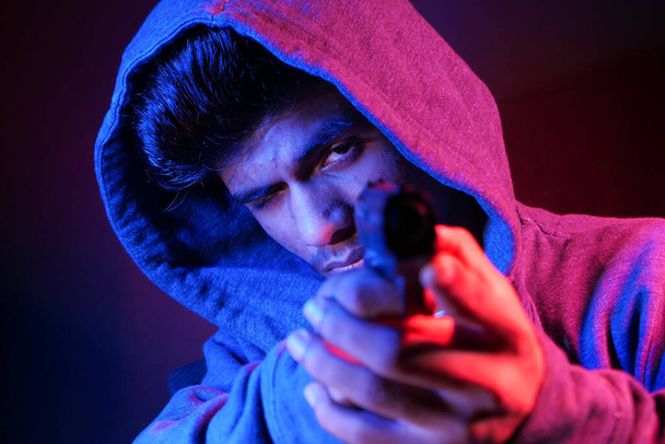 hooded man hand holding gun isolated on black  - Φωτογραφία, εικόνα