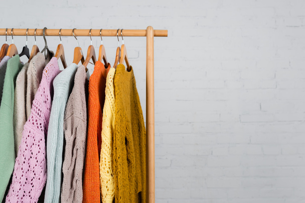 Wooden hanger rack with warm sweaters on white background - Фото, изображение