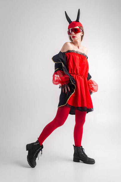 Sexy devil girl in red tights and black boots posing on white studio background. - Foto, afbeelding