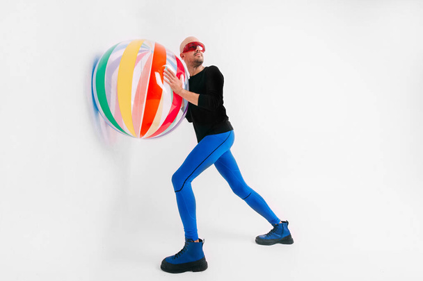 Athlete bald man in sportswear playing with beach ball in studio over white background. - Fotografie, Obrázek