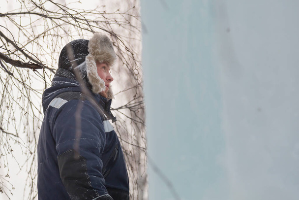 Retrato de un hombre con un sombrero de piel clara con una chaqueta de invierno azul en el lugar de trabajo - Foto, Imagen