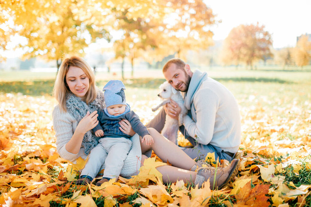 Happy family with their baby outdoor portrait in autumn park. - Foto, Imagem