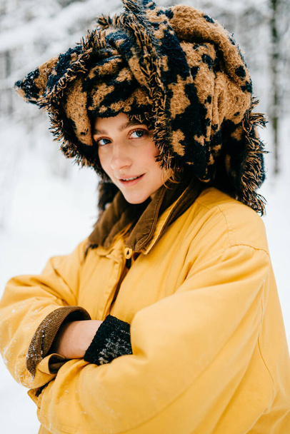 Funny young hipster girl in yellow jacket and turban of the scarf posing in the snow forest - Valokuva, kuva