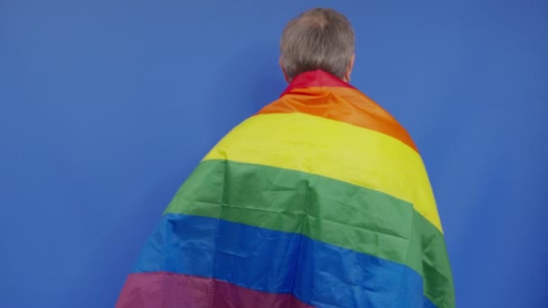 Homme âgé tenant le drapeau de la fierté de l'lgbt. Seule. Un seul. couvrant le drapeau LGBT. Drapeau LGBT sur fond bleu. - Séquence, vidéo