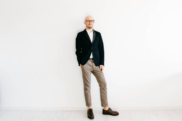 Tilt shift  soft portrait of businessman in expensive italian fashionable clothes standing indoors on white wall background and looking at camera. Handsome guy in designer jacket and cropped jeans.  - Valokuva, kuva