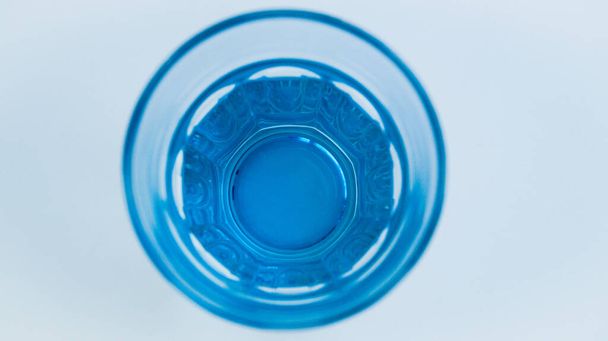 Blue glass with fresh purified drinking water on a light background. A glass of water in the morning on an empty stomach. A vital element of the human body. View from above. - 写真・画像