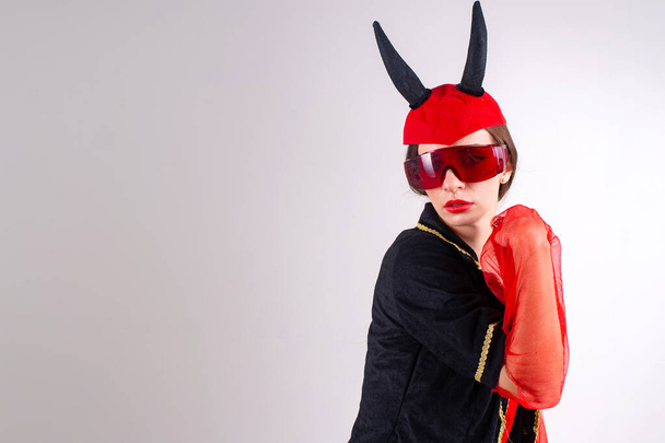 Studio fashion portrait of glamour sexy lady in futuristic glasses, black red carnival costume and devil horns on her head  - Φωτογραφία, εικόνα