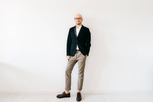 Tilt shift  soft portrait of businessman in expensive italian fashionable clothes standing indoors on white wall background and looking at camera. Handsome guy in designer jacket and cropped jeans.  - Foto, Imagen