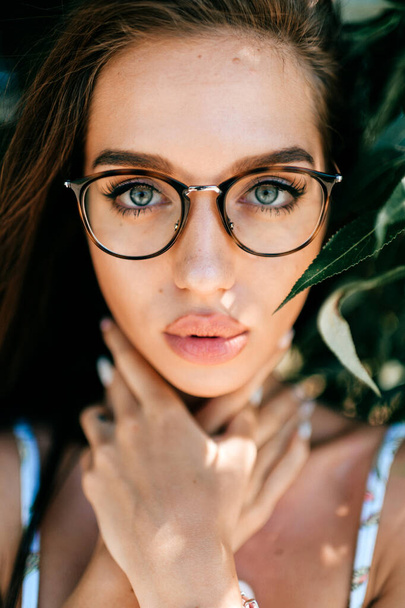 Closeup emotional artistic portrait of amazing fabulous beautiful young cheerful model girl with big natural lips and blue passionate eyes looking at camera outdoor at nature.  Cute lovely teen face - 写真・画像
