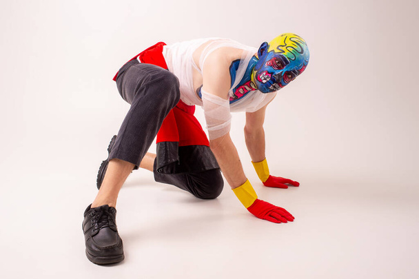 Strange man with makeup on his head and shoulder in white t-shirt, red and yellow gloves, red dances - Фото, зображення