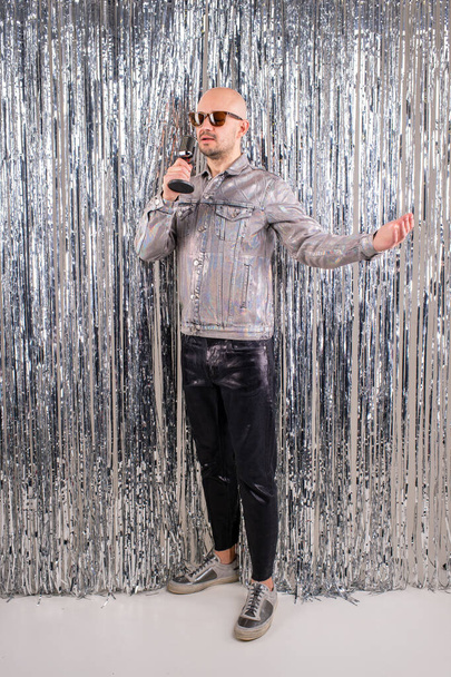 The 90s singer, wearing a silver shirt and leather pants, sings songs in the studio in isolation against a glittering backdrop - Foto, afbeelding