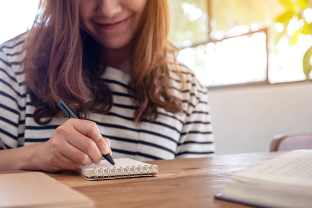 Zbliżenie obraz kobiety piszącej na pustym notatniku i książki na drewnianym stole podczas nauki - Zdjęcie, obraz