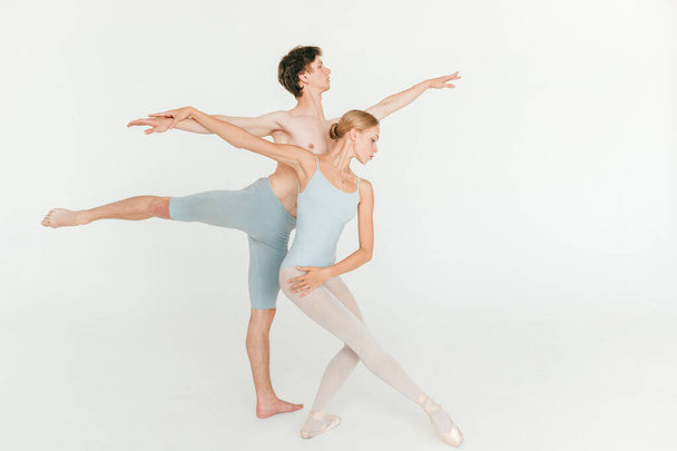 Two young classic ballet dancers practicing against white studio background - Fotó, kép