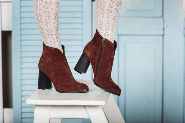 Botas de gamuza marrón para mujer. piernas delgadas de mujer en medias blancas - Foto, Imagen
