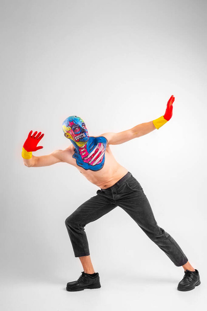 Strange man with makeup on his head and shoulder in white t-shirt, red and yellow gloves, red dances - Foto, immagini