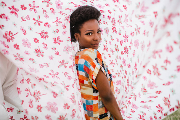 Fashion portrait of african american girl inside cover with flowers print - Фото, зображення