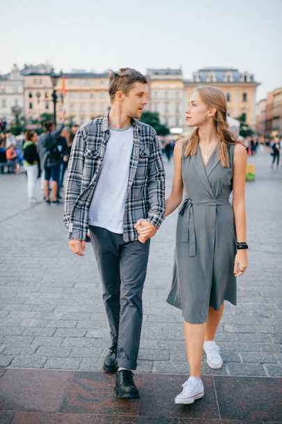 Счастливая любящая пара улыбается и ходит через главную площадь в Кракове (Краков)) - Фото, изображение
