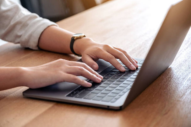 Zbliżenie obrazu dłoni kobiety za pomocą i wpisując na klawiaturze laptopa na stole - Zdjęcie, obraz