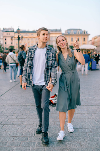 Happy loving couple smiling and walking throug the main square in Krakow (Cracow) - Foto, Imagem