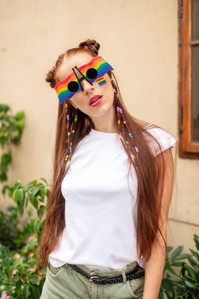 Happy bisexual woman with lgbt flag on her face and colorful sunglasses outdoor portrait - Fotografie, Obrázek