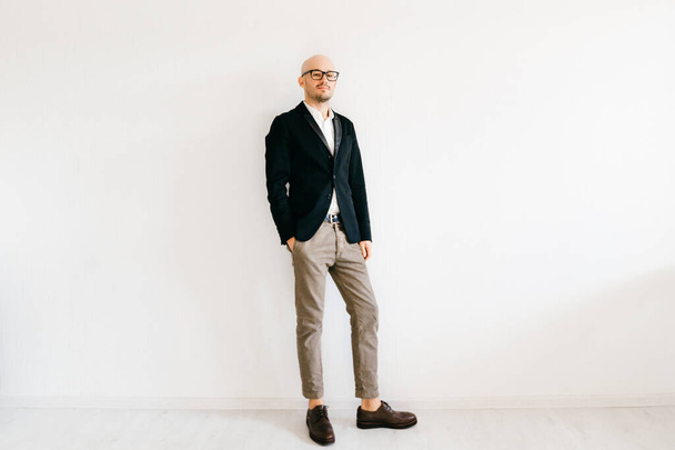 Tilt shift  soft portrait of businessman in expensive italian fashionable clothes standing indoors on white wall background and looking at camera. Handsome guy in designer jacket and cropped jeans.  - Foto, Imagem
