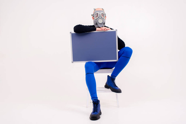 Funny strange man in respirator sitting on stepladder with a marker board  over white background - 写真・画像
