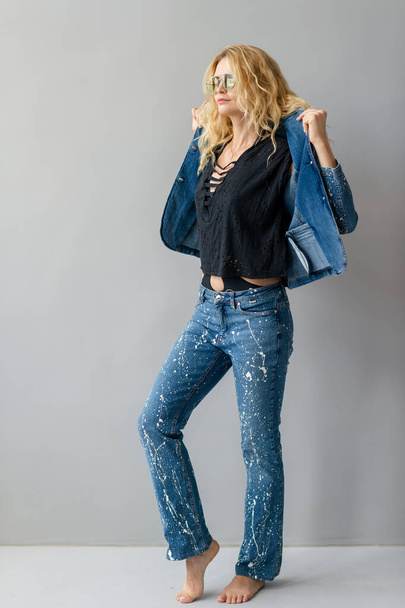 Beautiful stylish blonde model in jeans suit posing in studio - Photo, Image
