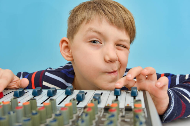 Müzik konsolunun başında oturan bir çocuk çamurluğu kontrol eder ve göz kırpar, müziğin sesini yükseltir.. - Fotoğraf, Görsel