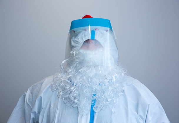 Papá Noel con traje médico protector y máscara. Protección contra virus. Celebración de año nuevo en cuarentena. Coronavirus (COVID-19). - Foto, Imagen