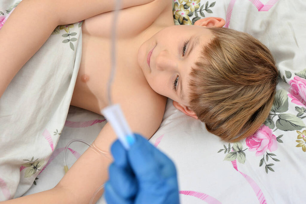 Un garçon malade est couché, le médecin lui prépare un antibiotique.. - Photo, image
