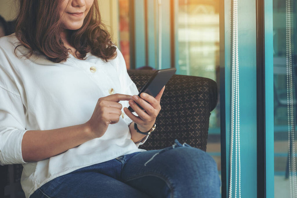 Nahaufnahme einer Frau, die im Café ein Smartphone hält, benutzt und auf dieses zeigt - Foto, Bild
