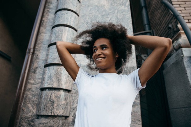 Nahaufnahme Porträt einer attraktiven afroamerikanischen Frau mit Frisur im Hintergrund der Stadt. Black lives matter Konzept - Foto, Bild
