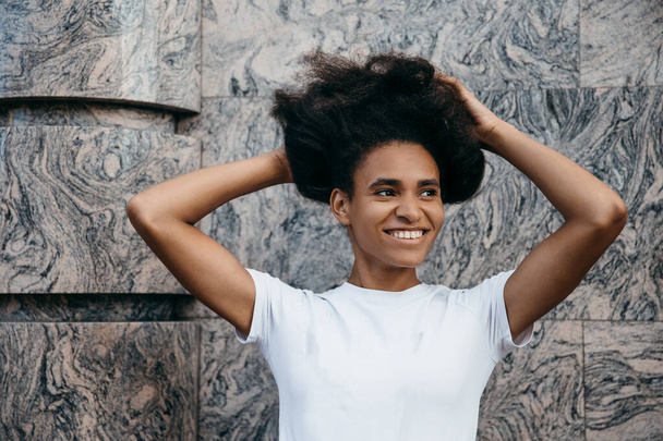 Ritratto ravvicinato di attraente donna afro americana con acconciatura sullo sfondo della città. Concetto di vita nera - Foto, immagini